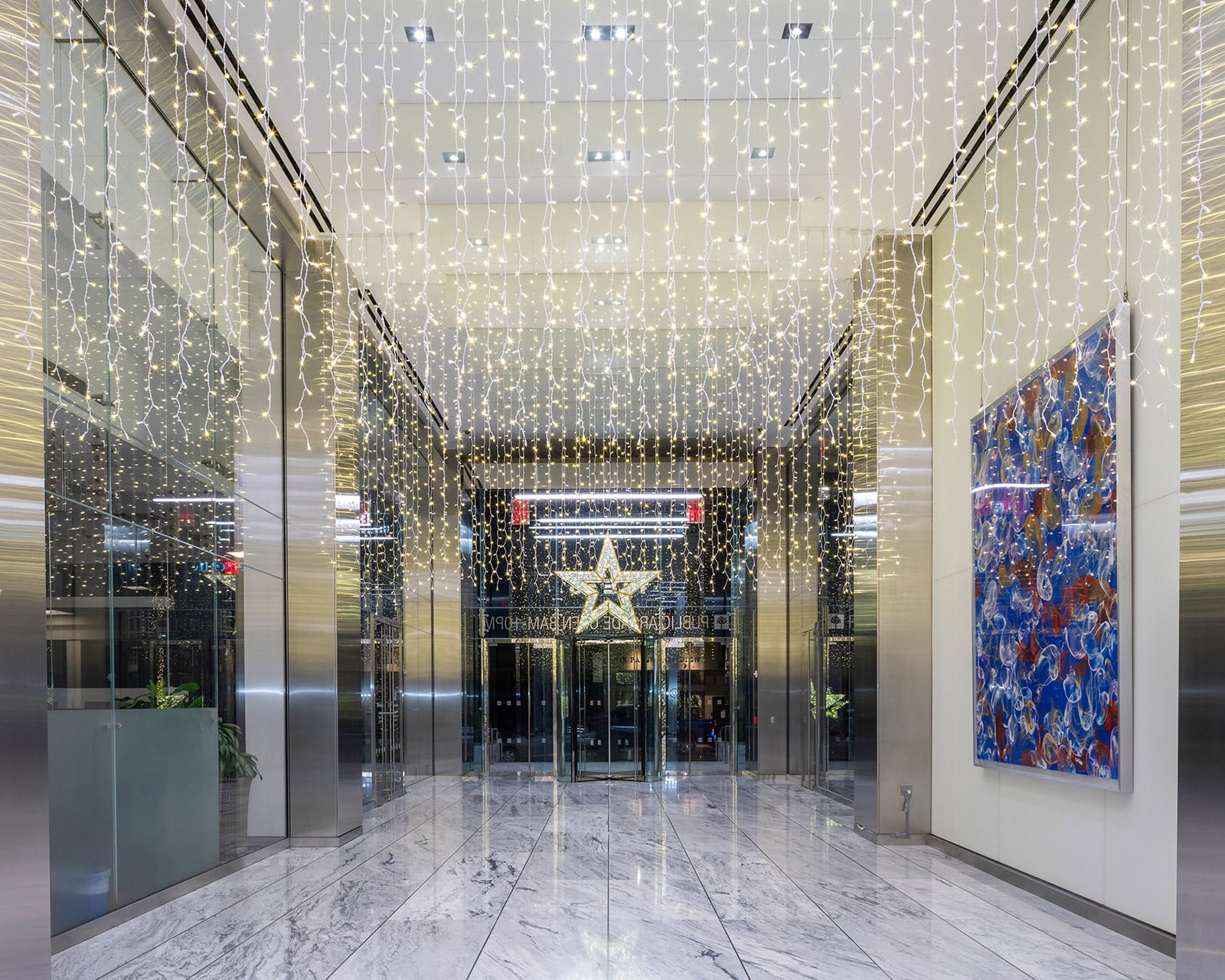 Cambridge portfolio showing a curtain of warm white holiday lights in a modern corporate lobby for high-rise residences in Jersey City